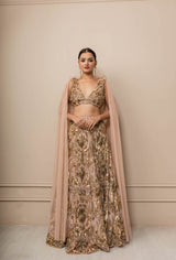 Woman wearing a traditional outfit with a beige and gold color scheme against a neutral background