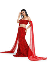Crimson Reign Lehenga by DEEPANSHI MASSEY LABEL showcasing a fitted mermaid silhouette, embellished off-shoulder blouse and long flowing red net trail sleeves with handcrafted detailing.