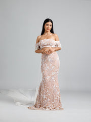 Full-length view of the beige fish cut lehenga by DEEPANSHI MASSEY LABEL, featuring intricate floral embroidery, an off-shoulder pearl-fringed blouse, and a trailing pearl-embellished cape.
