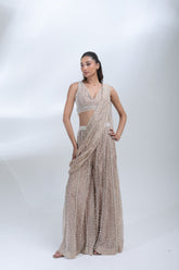 Opaline Sharara by DEEPANSHI MASSEY LABEL featuring a champagne beige tissue ensemble with intricate pearl embellishments, sleeveless V-neck blouse and flowing sharara pants.