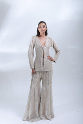 Full-length front view of a model wearing a champagne beige pearl-embellished jacket and matching wide-leg trousers.