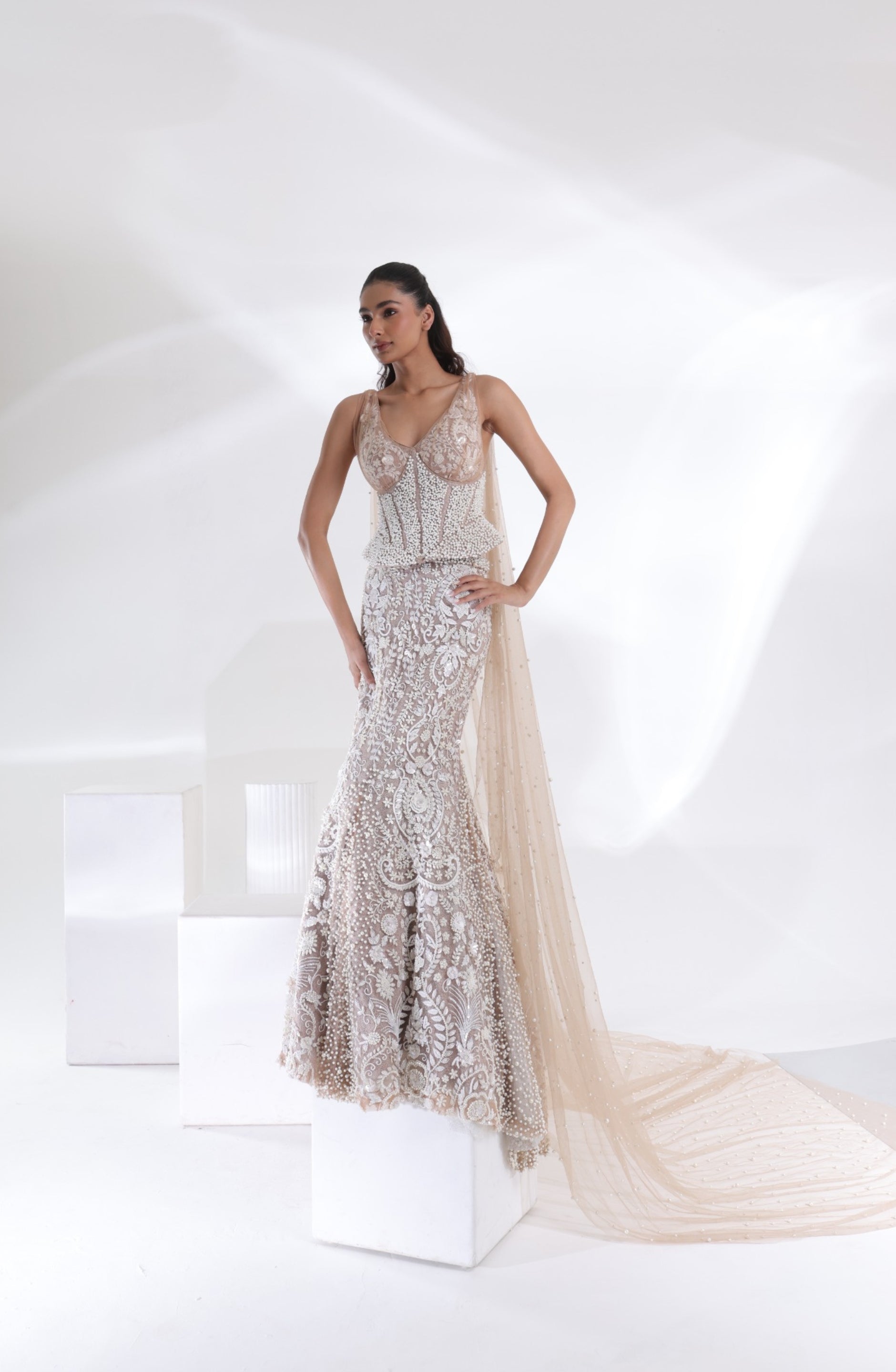 Aurelia Pearl Mermaid Lehenga featuring a pearl-embellished corset blouse, intricate floral embroidery and a long sheer champagne ivory veil arranged in an elegant bridal silhouette by DEEPANSHI MASSEY LABEL.
