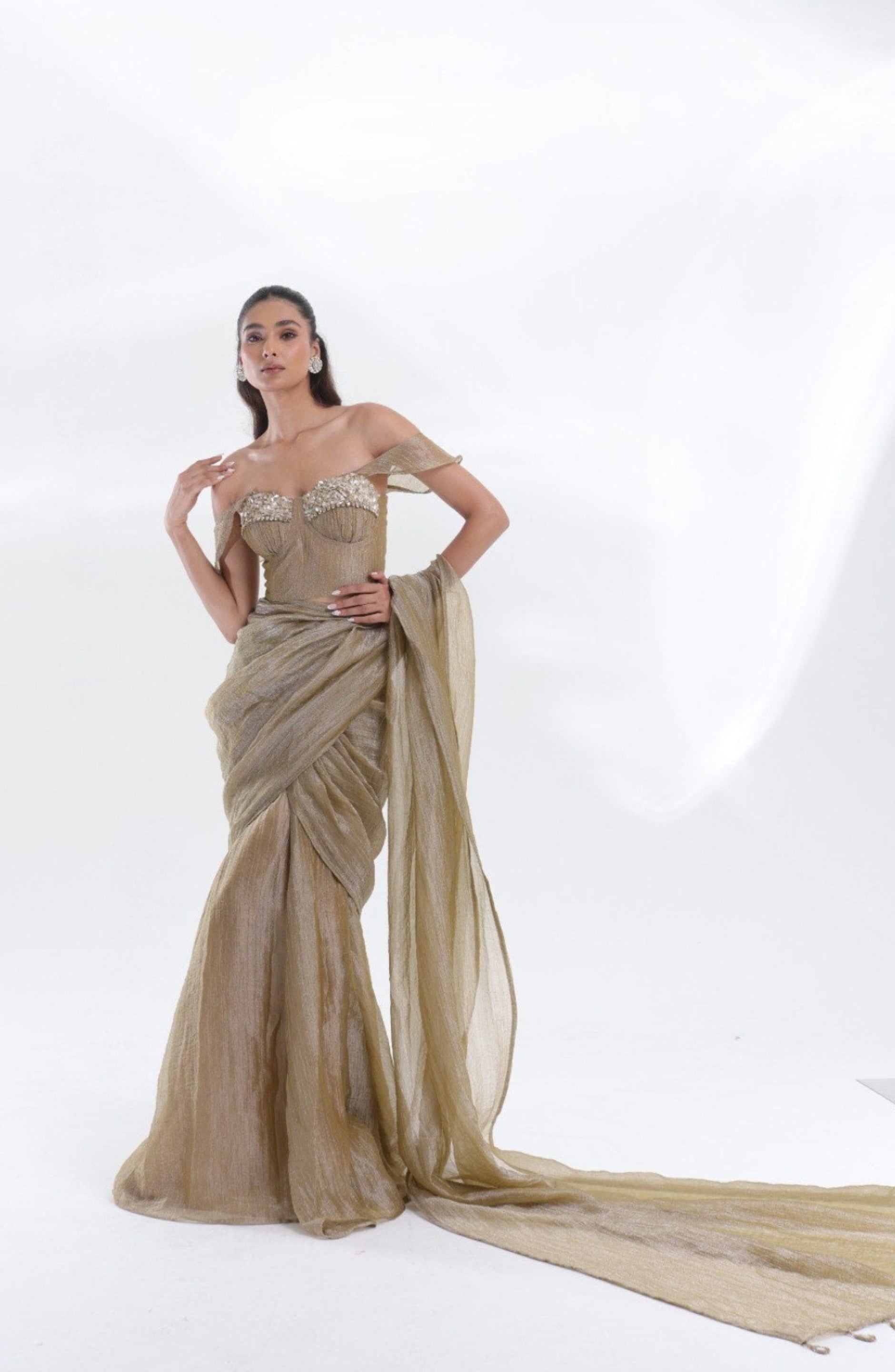 Aurum Tissue Silk Saree by DEEPANSHI MASSEY LABEL showcasing a full-length champagne-gold designer saree with a statement embellished corset blouse and a dramatic floor-length pallu.