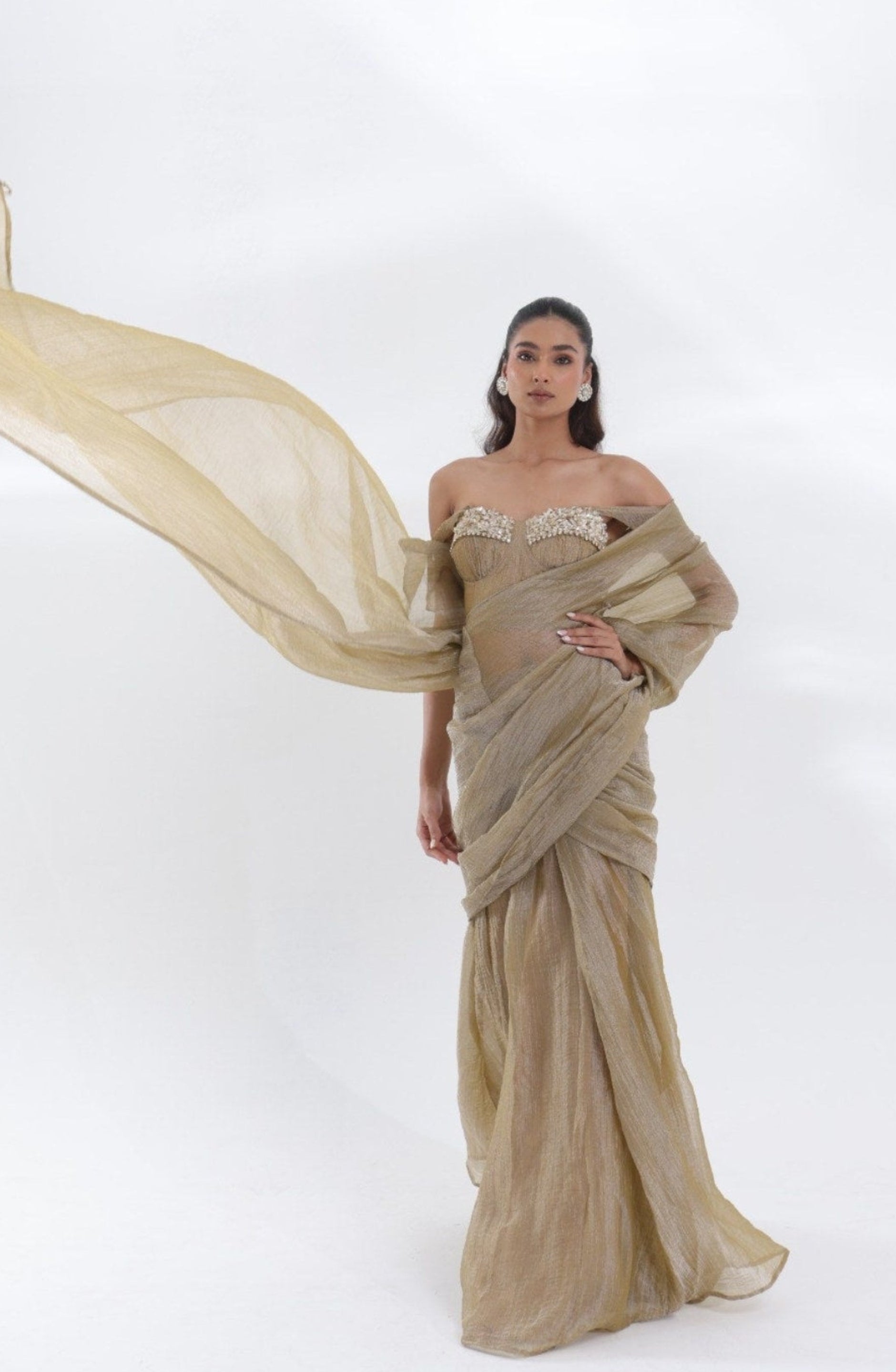 Aurum Tissue Silk Saree by DEEPANSHI MASSEY LABEL styled with a flowing champagne-gold pallu and an embellished off-shoulder corset blouse, perfect for weddings, receptions and luxury celebrations.