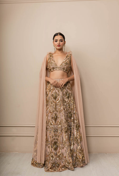 Woman wearing a traditional outfit with a beige and gold color scheme against a neutral background
