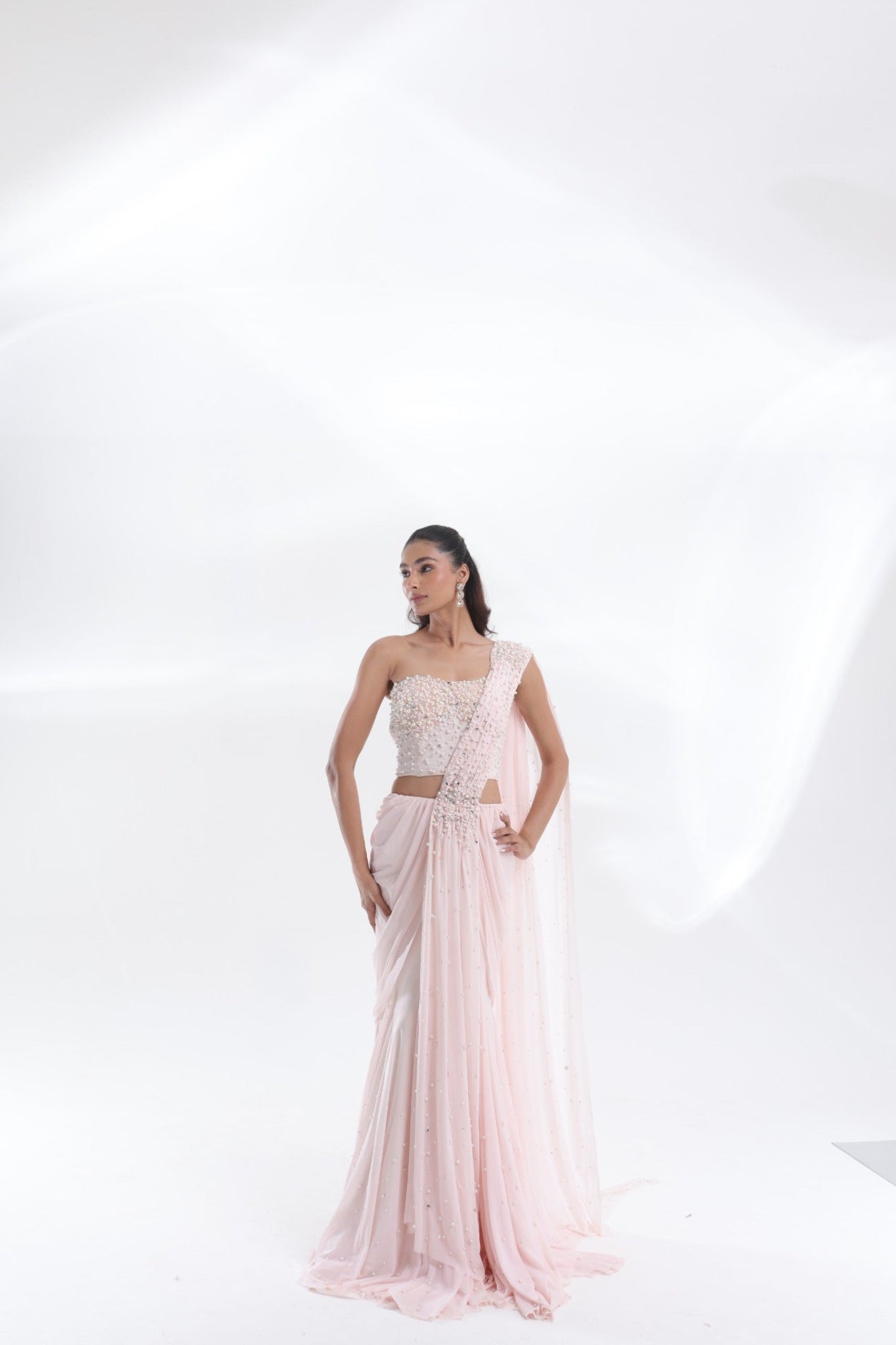 DEEPANSHI MASSEY LABEL baby pink saree lehenga with pearl-work blouse and draped pallu, elegant full-length three-quarter pose
