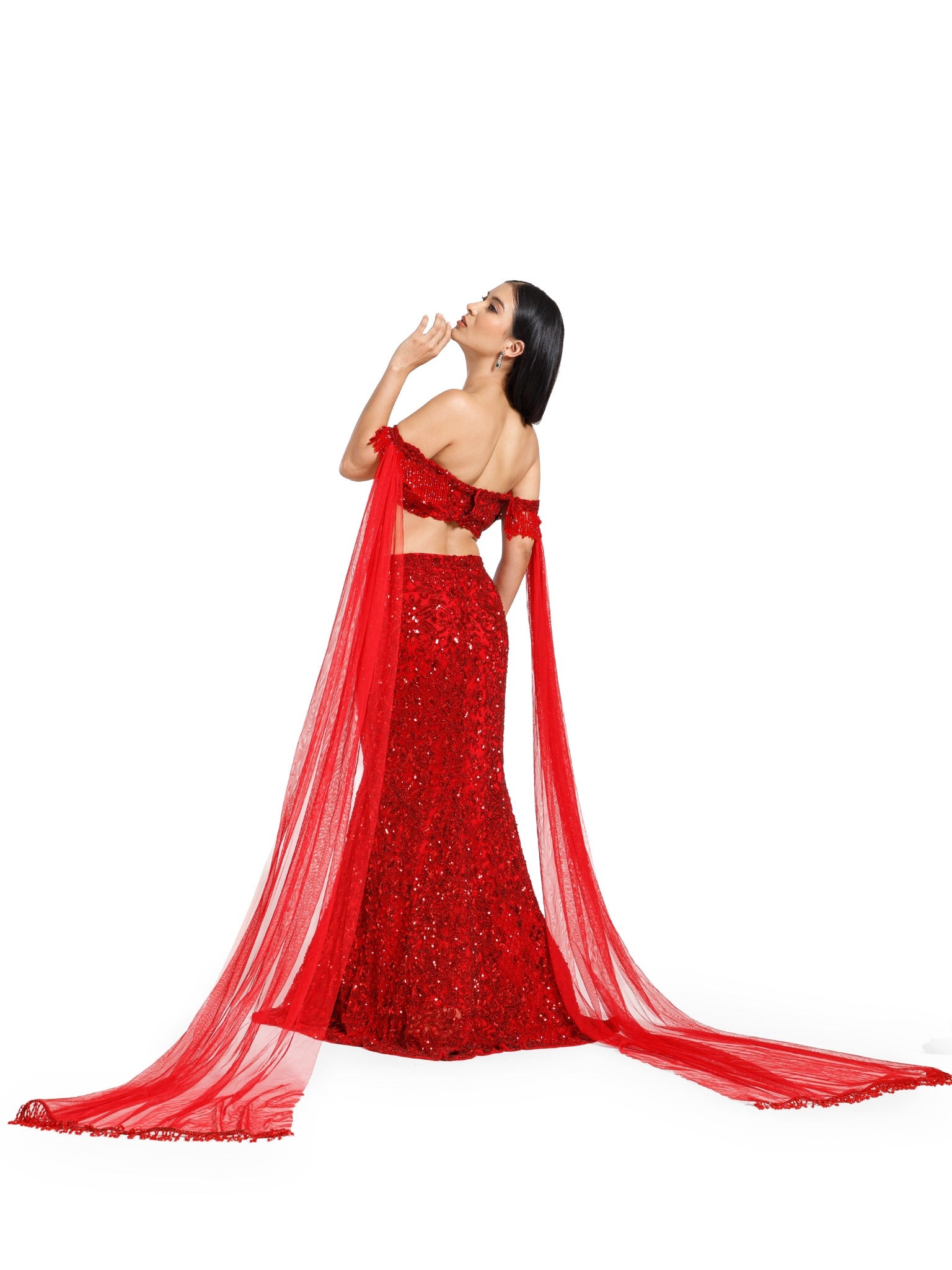 Back view of the Crimson Reign Lehenga by DEEPANSHI MASSEY LABEL featuring an embroidered red mermaid skirt, off-shoulder blouse and long detachable net trail sleeves.