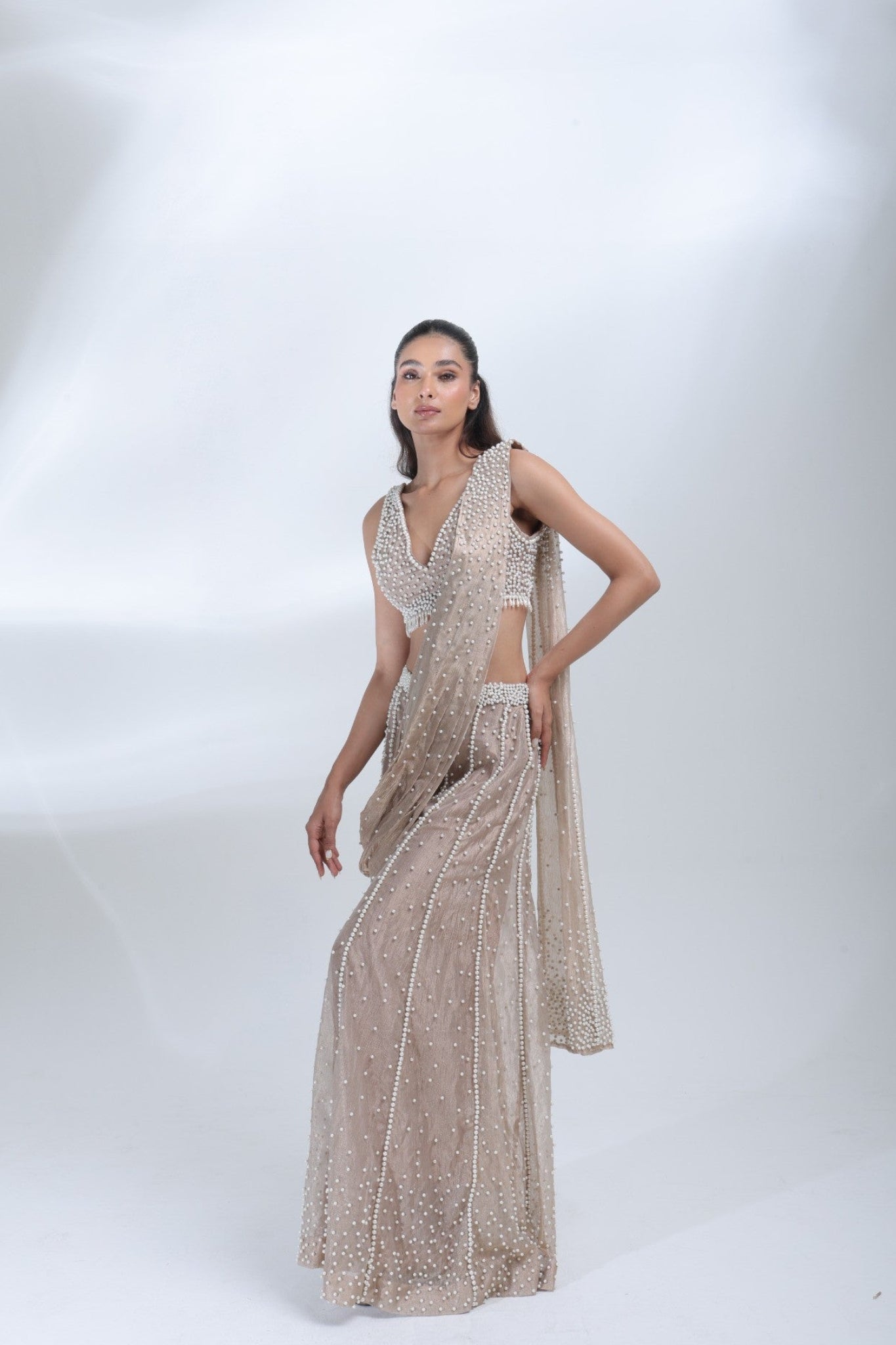 Opaline Sharara by DEEPANSHI MASSEY LABEL showcasing a pearl-embellished champagne tissue outfit with a sleeveless blouse, draped dupatta and elegant wide-leg sharara pants.