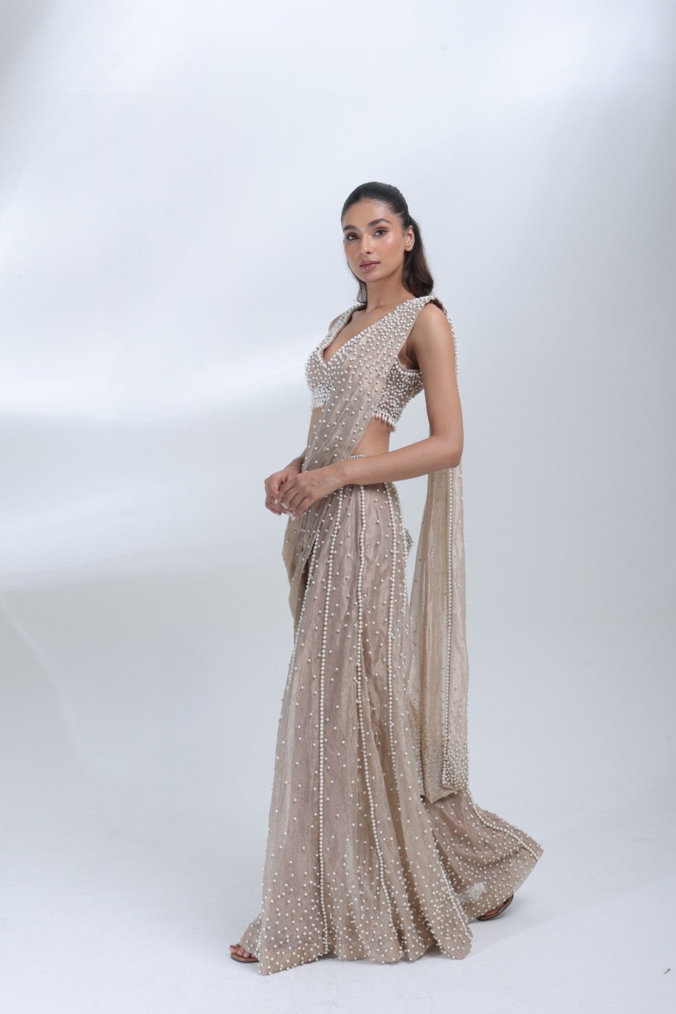 Side profile of the Opaline Sharara by DEEPANSHI MASSEY LABEL highlighting its champagne tissue fabric, pearl detailing, fitted blouse and flowing sharara silhouette.
