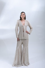 Full-length front view of a model wearing a champagne beige pearl-embellished jacket and matching wide-leg trousers.