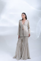 Side-angle view of the champagne pearl-embellished jacket and flowing wide-leg trousers.