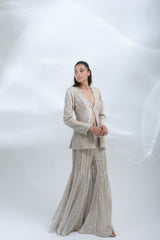 Three-quarter pose showcasing the pearl detailing and elegant silhouette of the champagne jacket and trouser set.