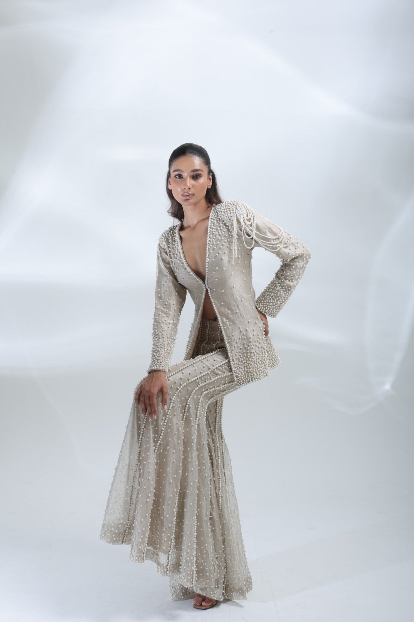 Full-length fashion pose highlighting the pearl-embellished jacket and matching flared trousers.
