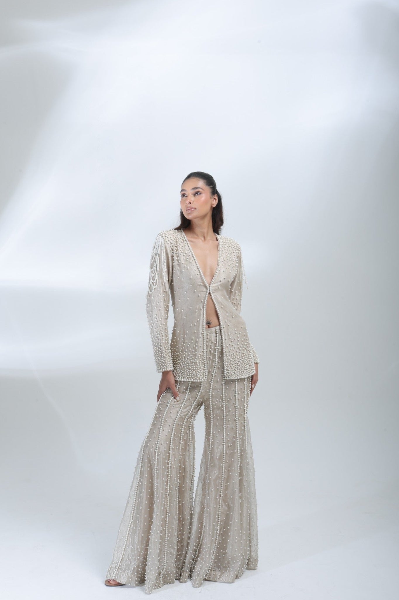 Full-length three-quarter view of the champagne pearl co-ord set with statement shoulder detailing.